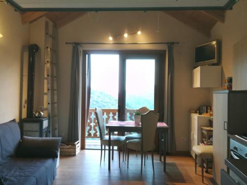 een woonkamer met een tafel en stoelen en een raam bij LA PICCIONAIA in Varallo