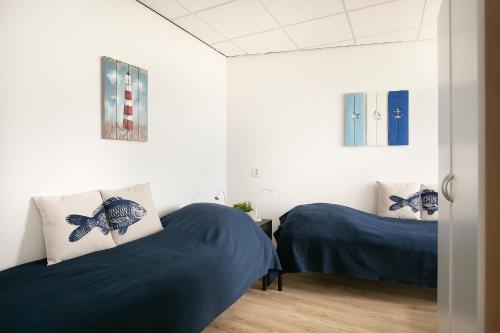 two beds in a room with white walls at Strandappartement Duynblick in Julianadorp