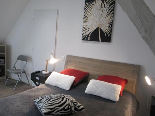 a bedroom with a bed with red and white pillows at La Ferme de la Chapelle-Saint-Jean in Beynat