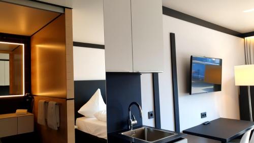 a bathroom with a sink and a tv on the wall at ILL Hotel by WMM Hotels in Illertissen