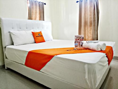 a white bed with an orange and white blanket at WISMA ANDALI Syariah near RSUD Cideres in Majalengka