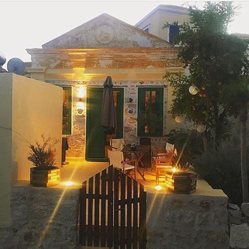 a house with a patio with a table and a umbrella at Hypate, traditional island cottage in Halki