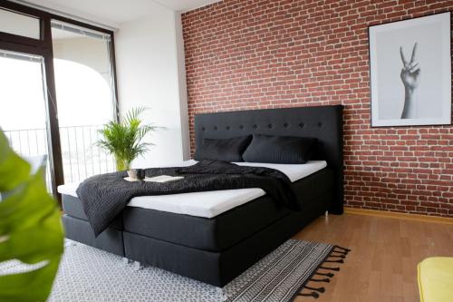 um quarto com uma cama contra uma parede de tijolos em Tolles Apartment mit Weitblick über Augsburg em Augsburg