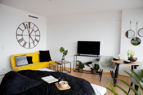 ein Wohnzimmer mit einem gelben Sofa und einem TV in der Unterkunft Tolles Apartment mit Weitblick über Augsburg in Augsburg