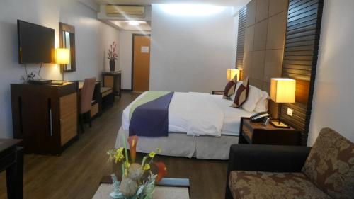 ein Hotelzimmer mit einem Bett und einem Sofa in der Unterkunft Circle Inn Hotel and Suites Bacolod in Bacolod City