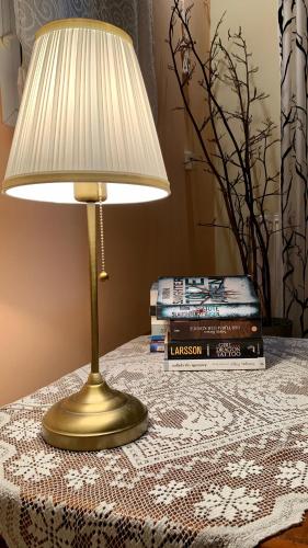 a lamp sitting on a table with a stack of books at Wooden Roof Apartment in Lixouri