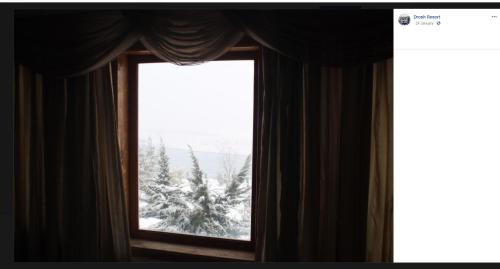 een raam met uitzicht op een met sneeuw bedekte boom bij Drosh Resort in Chitral