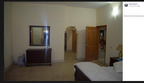 een slaapkamer met een bed, een dressoir en een spiegel bij Drosh Resort in Chitral