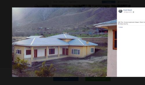 een klein geel huis met een berg op de achtergrond bij Drosh Resort in Chitral