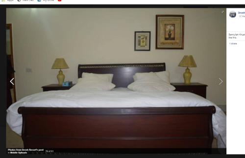 een slaapkamer met een bed met witte lakens en 2 lampen bij Drosh Resort in Chitral