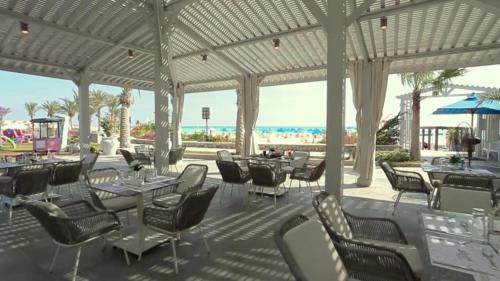 a restaurant with tables and chairs and the beach at Mirage Hotel Sidi Abd El Rahman in El Alamein