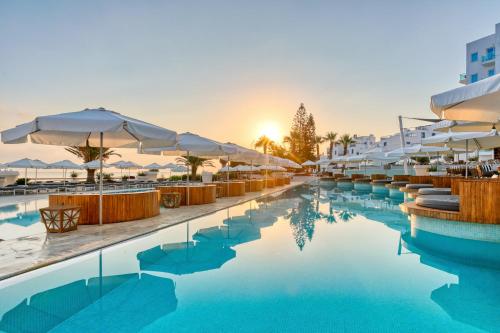 a hotel pool with umbrellas and chairs at King Jason Protaras - Designed for Adults by Louis Hotels in Protaras