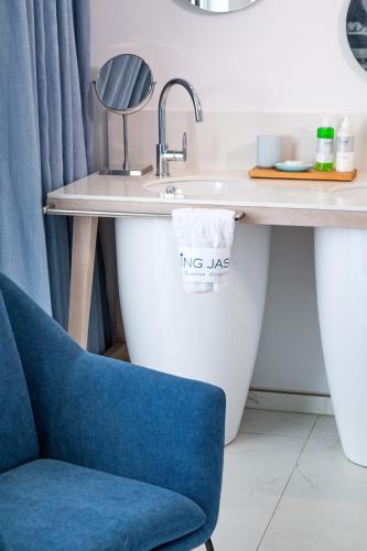 a bathroom with a sink and a blue chair at King Jason Protaras - Designed for Adults by Louis Hotels in Protaras