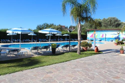 a swimming pool with chairs and umbrellas at Villaggio & Residence Club Aquilia in Badolato