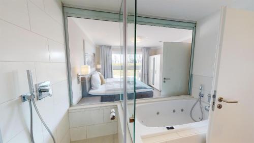 a bathroom with a tub and a shower with a mirror at Beach'n'Sea Wohnung 2 in Grömitz