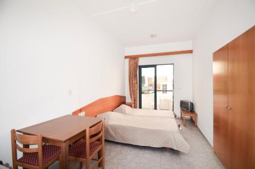 1 dormitorio con cama, mesa y ventana en Stegna Star Apartments en Archangelos