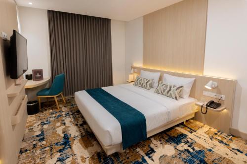 a hotel room with a large bed and a desk at Cordia Hotel Yogyakarta - Hotel Dalam Bandara in Glagah