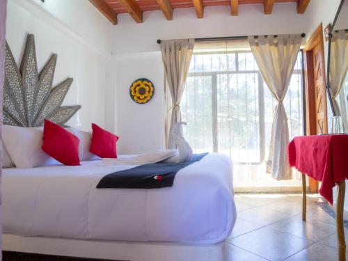 Un dormitorio con una cama blanca con almohadas rojas y una ventana. en Valle Dorado, en Valle de Bravo