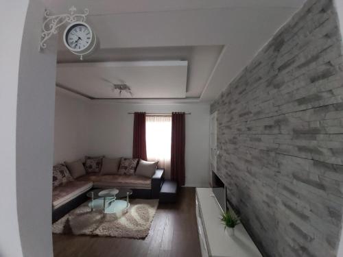 a living room with a couch and a clock on the wall at Guest house Vlahovic in Kolašin