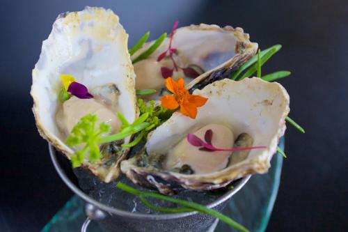 a glass dish of oysters with flowers on it at Karma St. Martin's in St Martins