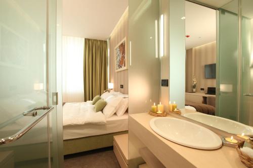 W łazience znajduje się łóżko, umywalka i lustro. w obiekcie Hotel Argo w Belgradzie