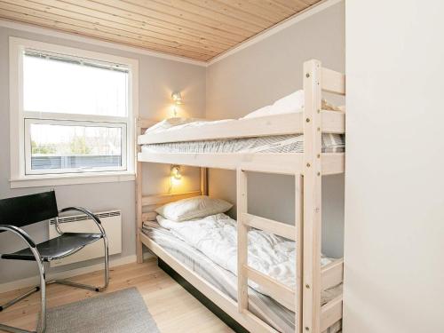 a bedroom with bunk beds with a desk and a chair at Three-Bedroom Holiday home in Væggerløse 6 in Bøtø By