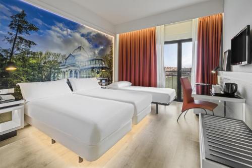 a hotel room with two beds and a tv at Elba Madrid Alcalá in Madrid