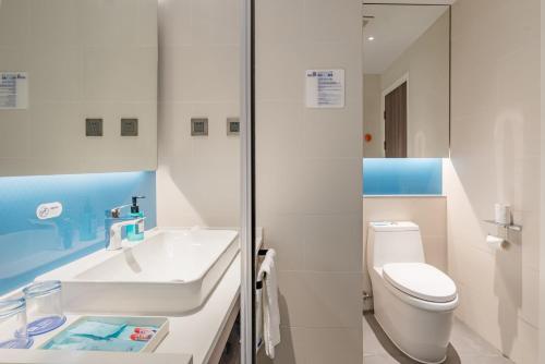 a white bathroom with a toilet and a sink at Holiday Inn Express Taian City Center by IHG in Tai'an