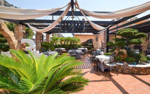 un patio con tavoli, sedie e baldacchino di Coralli Apartments a Pefki Rhodes