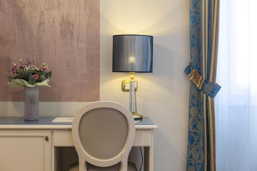 a desk with a chair and a lamp and a vase of flowers at Hotel Donatello in Florence