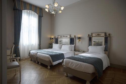 a bedroom with two beds and a chandelier at Hotel Donatello in Florence