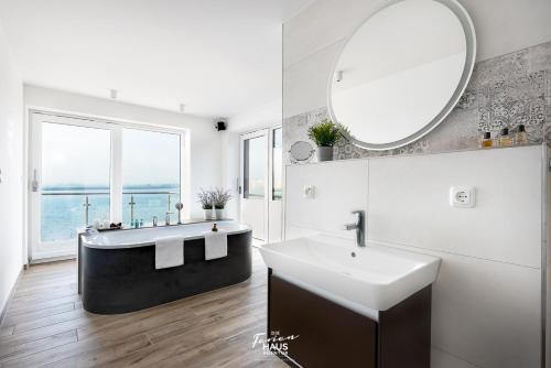 a bathroom with a tub and a sink and a mirror at Sea 65 in Olpenitz