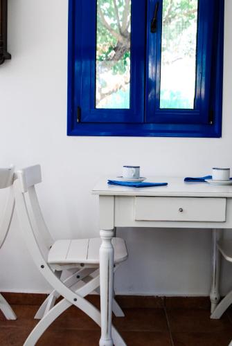 - un bureau blanc avec une chaise et un miroir dans l'établissement Katikies Studios & Apartments, à Lardos