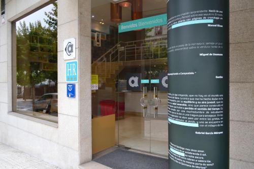 a building with a sign in front of a store at Hotel Alda San Carlos in Santiago de Compostela