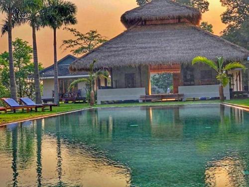 een zwembad voor een gebouw met palmbomen bij Khla Lodge in Kampot