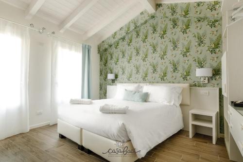 um quarto com uma cama branca e papel de parede floral em CASA BACI - Soggiorno nel Gusto em Colà di Lazise