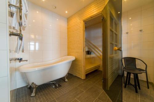 La salle de bains est pourvue d'une baignoire et d'une chaise. dans l'établissement Hornavan Hotell, à Arjeplog