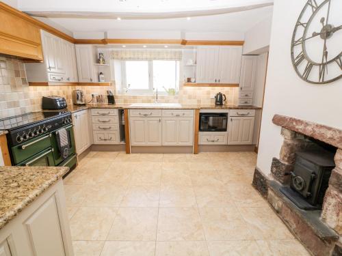 a kitchen with a large clock on the wall at The Farmhouse in Biddulph