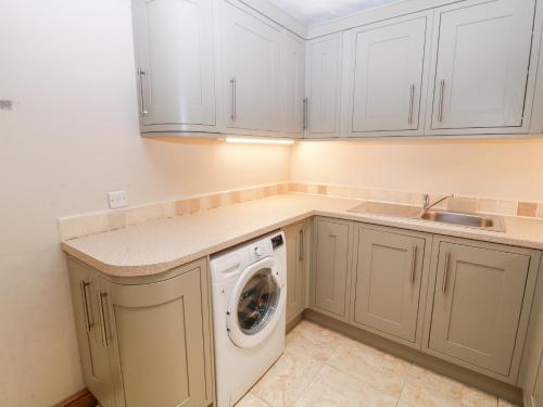 a kitchen with white cabinets and a washing machine at The Farmhouse in Biddulph