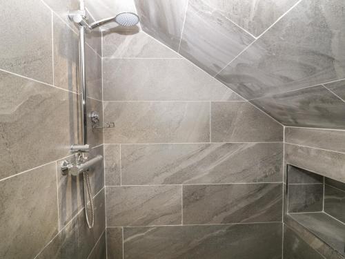 a shower in a bathroom with a stone wall at The Farmhouse in Biddulph