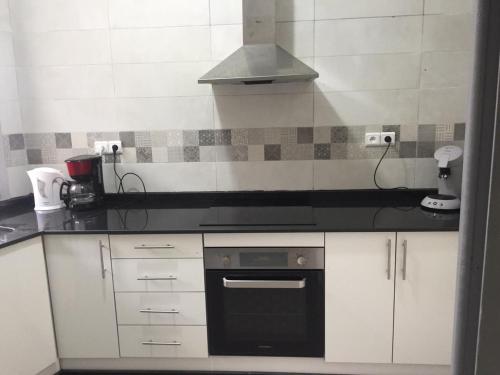 a kitchen with white cabinets and a black oven at Appartement hyper centre de Tanger (Boulevard Pasteur) in Tangier