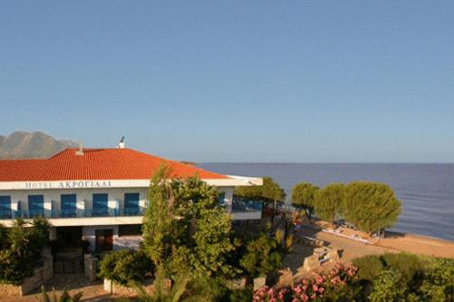 a building with a red roof next to the ocean at Akrogiali in Kyparissia