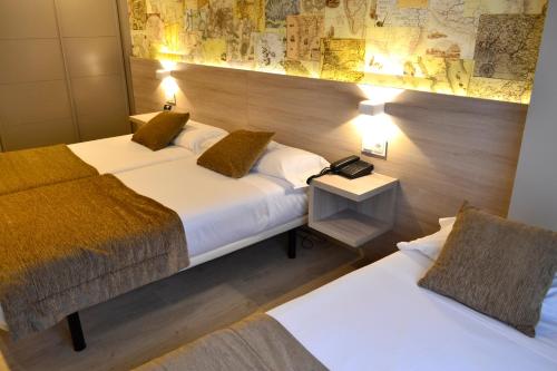 a hotel room with two beds and a map on the wall at Hotel Alda San Carlos in Santiago de Compostela
