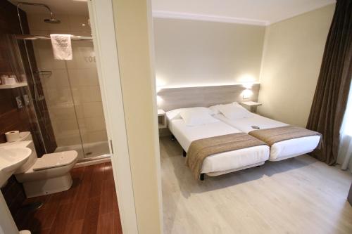 a hotel room with a bed and a bathroom at Hotel Alda San Carlos in Santiago de Compostela