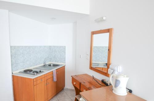 a kitchen with a sink and a mirror at Palm Bay Hotel in Pefki