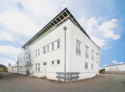 a white building with a bench in front of it at Pension Schweizer in Laupheim