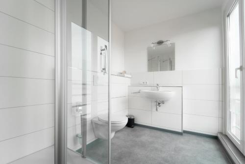 a white bathroom with a toilet and a sink at Pension Schweizer in Laupheim