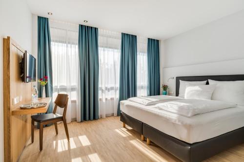 a bedroom with a bed and a desk with a chair at Hotel Apfelrot in Erding