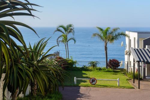 a view of the ocean from a house with palm trees at Sands Beach Breaks Umdloti Beach View in Umdloti