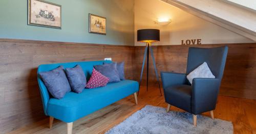 a blue couch and a chair in a room at Hotel Natur-Landhaus Krone in Maierhöfen